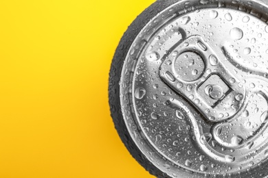 Photo of Wet closed can on yellow background, closeup. Space for text