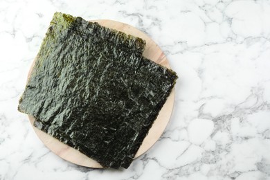 Photo of Dry nori sheets on white marble table, top view. Space for text