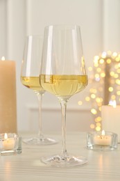 Photo of Glasses of wine and candles on wooden table