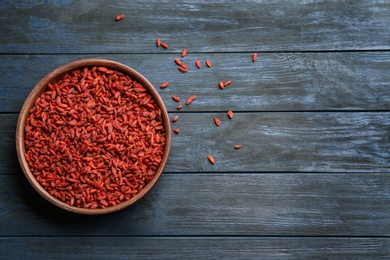 Photo of Bowl of dried goji berries on wooden table, top view with space for text. Healthy superfood