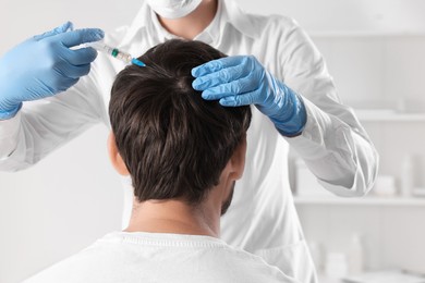 Trichologist giving injection to patient in clinic, closeup