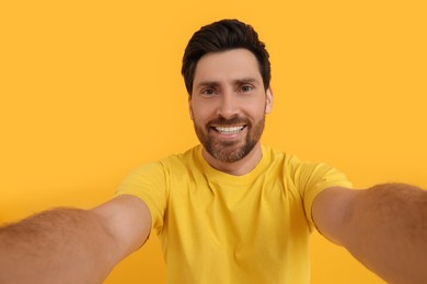 Photo of Smiling man taking selfie on yellow background