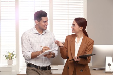 Businesswoman helping intern with work in office