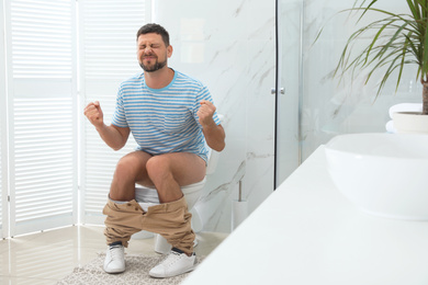 Man suffering from hemorrhoid on toilet bowl in rest room