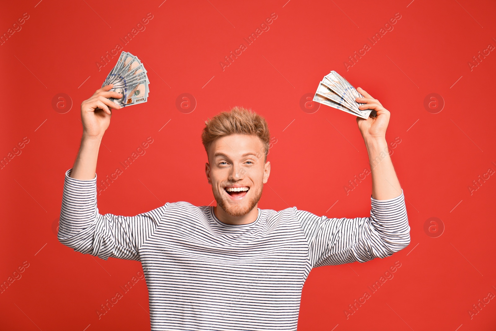 Photo of Portrait of happy lottery winner with money on red background