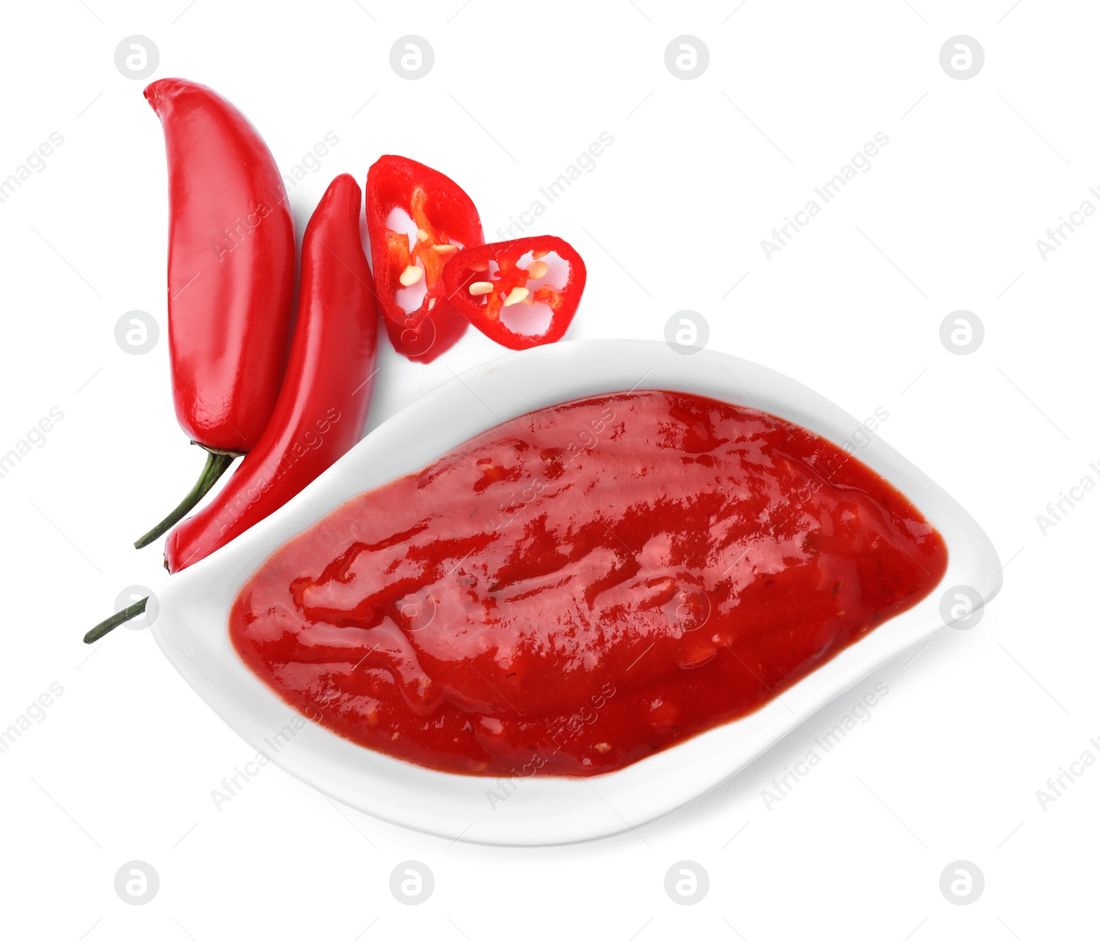 Photo of Gravy boat with red sauce and fresh chili peppers isolated on white, top view