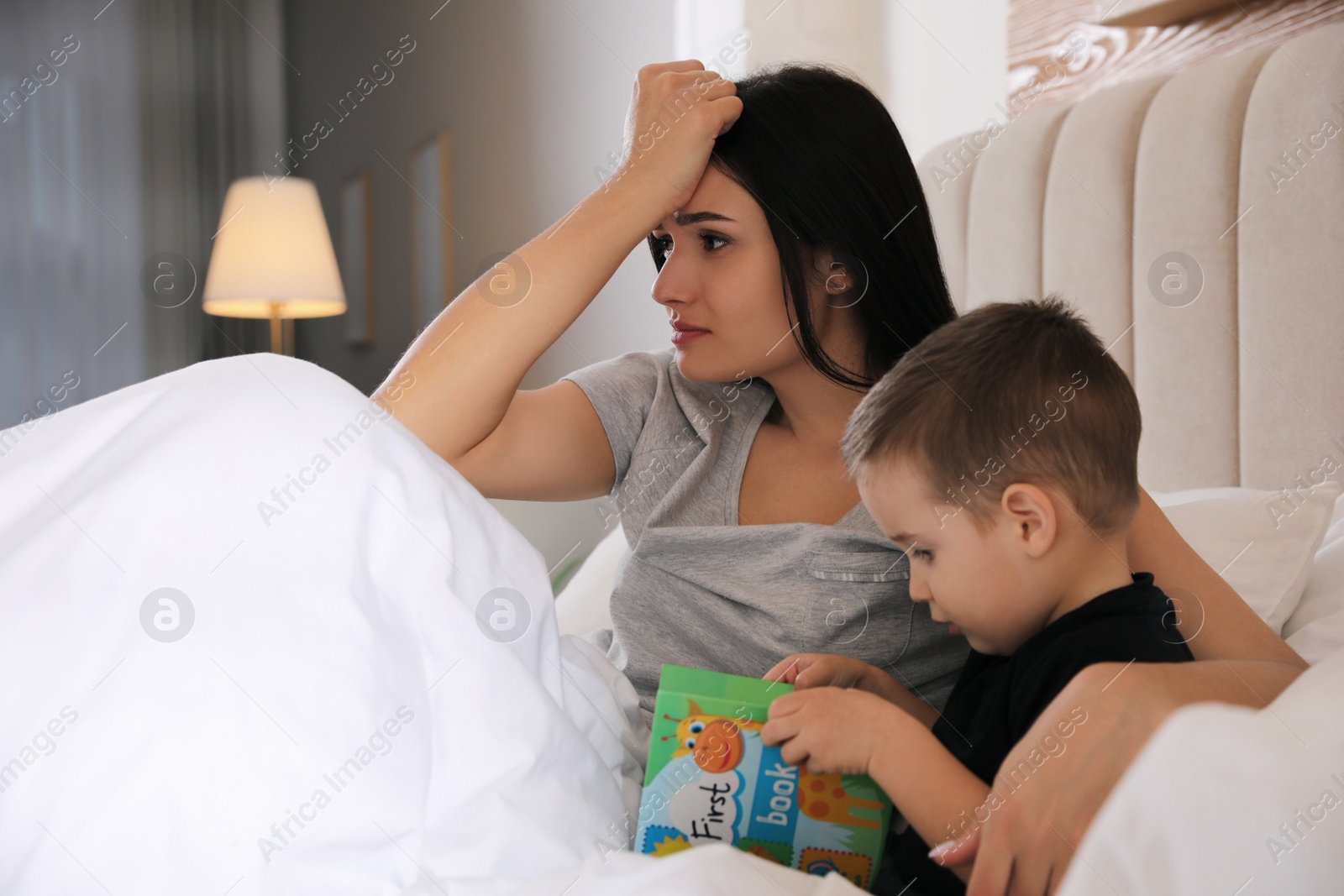 Photo of Depressed single mother with child in bed at home