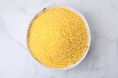 Raw cornmeal in bowl on white marble table, top view