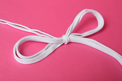 Photo of White shoe laces tied in bow on pink background