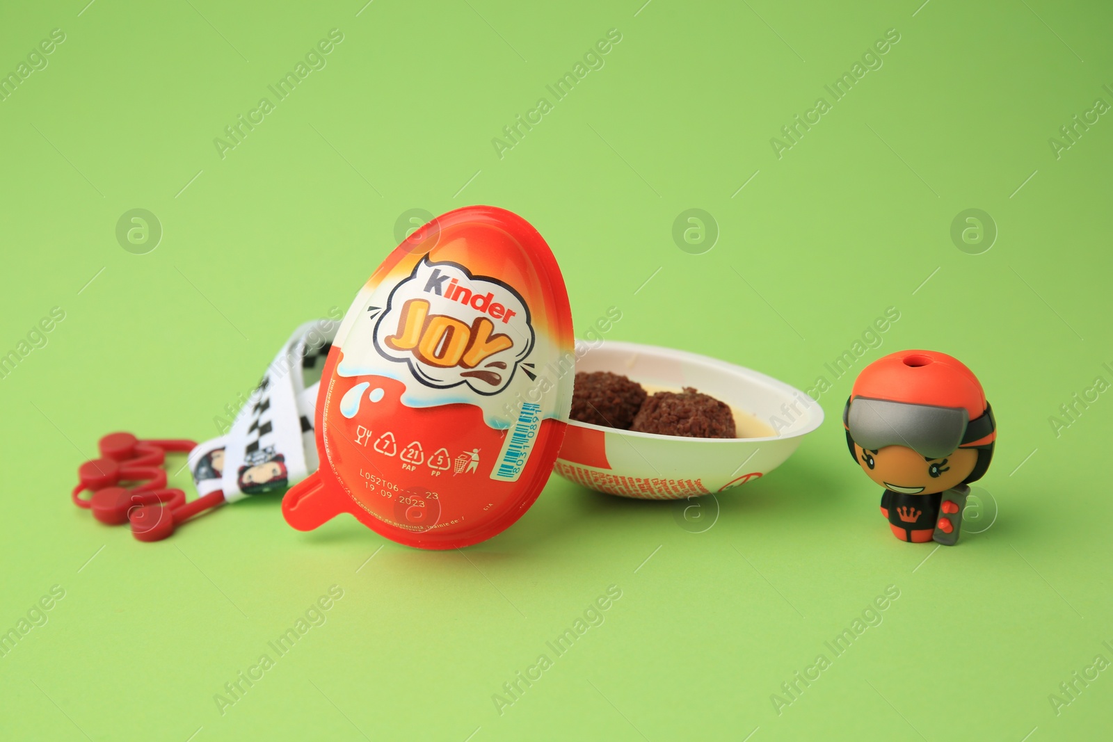 Photo of Sveti Vlas, Bulgaria - June 29, 2023: Halves of Kinder Joy Egg with sweet candies and toys on light green background