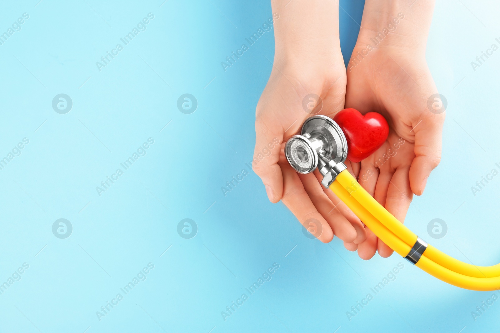 Photo of Woman holding red heart and stethoscope on color background. Heart attack concept