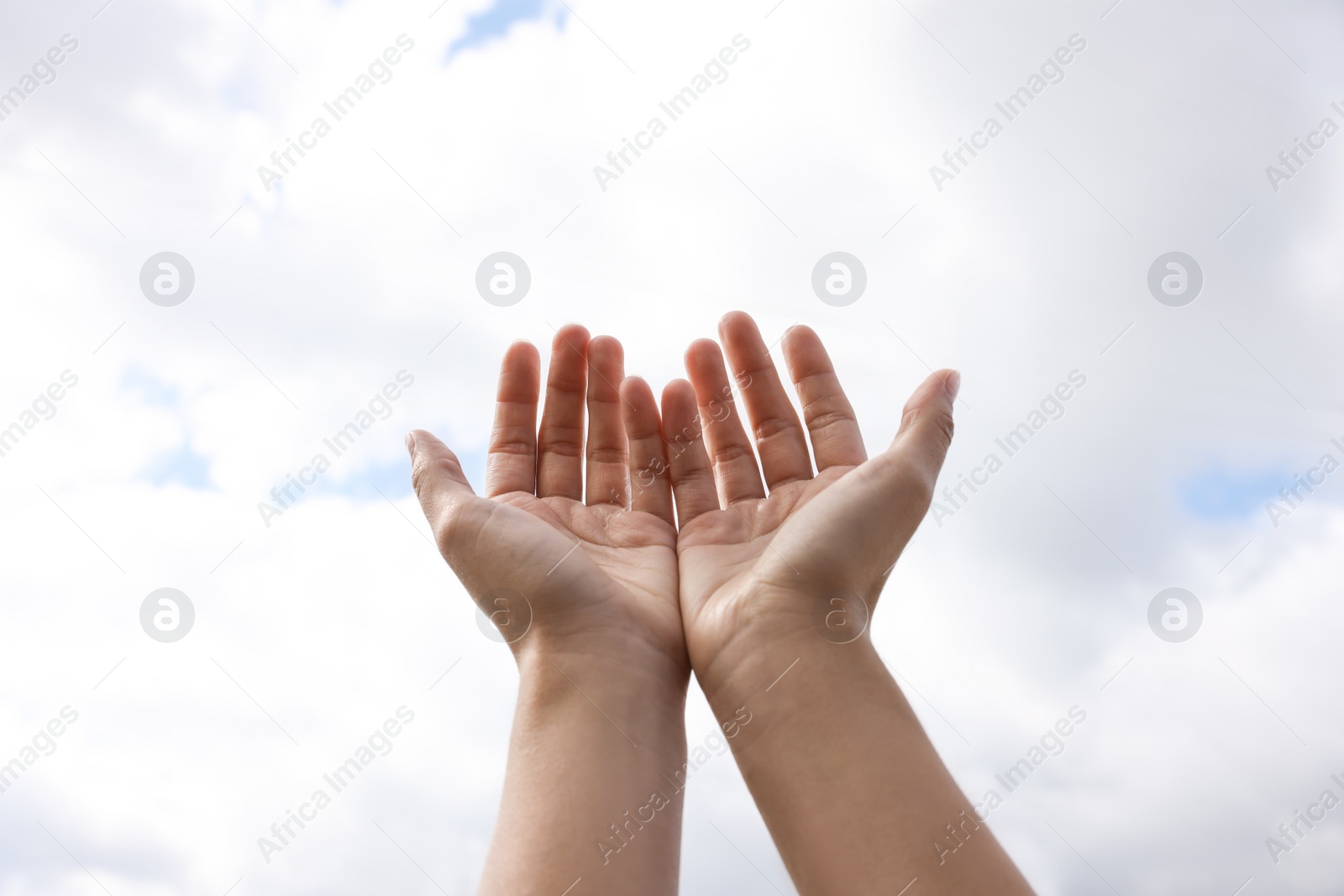 Photo of Woman reaching hands to blue sky outdoors on sunny day, closeup