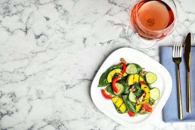 Delicious avocado salad served with glass of wine on marble table, flat lay. Space for text