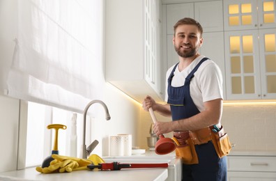 Photo of Plumber with plunger near clogged sink in kitchen
