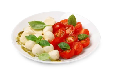 Photo of Plate of tasty Caprese salad with mozzarella, tomatoes, basil and pesto sauce isolated on white