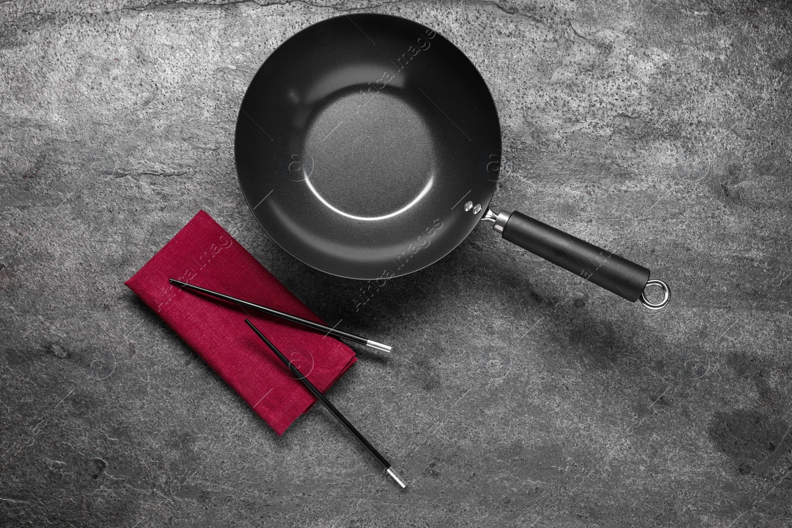 Photo of Empty iron wok and chopsticks on grey table, flat lay