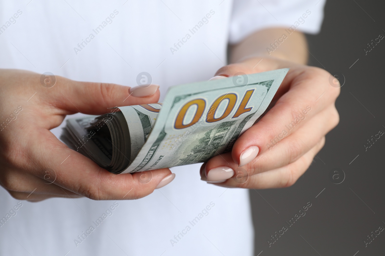 Photo of Money exchange. Woman counting dollar banknotes on grey background, closeup