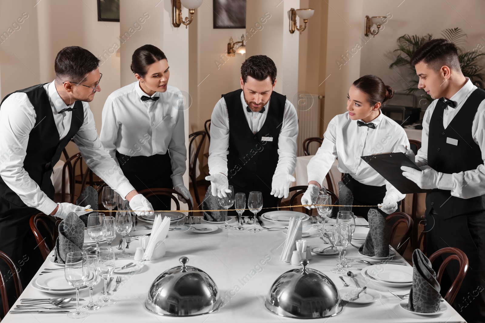 Photo of People setting table during professional butler courses in restaurant