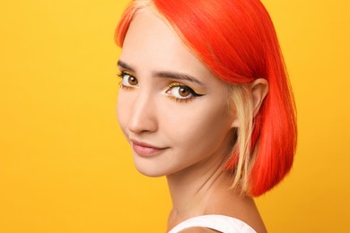 Photo of Beautiful young woman with bright dyed hair on orange background, closeup