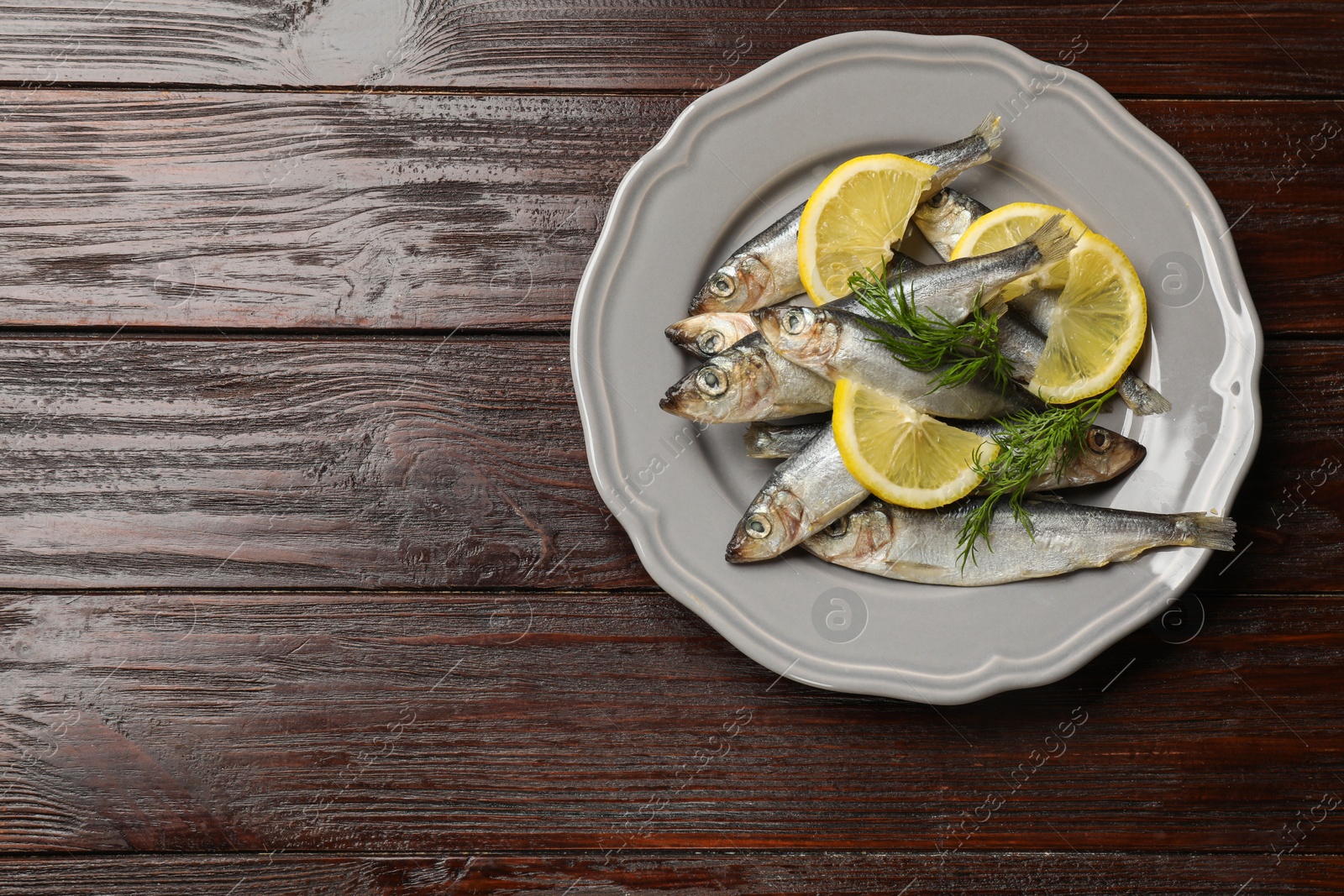 Photo of Fresh raw sprats, dill and cut lemon on wooden table, top view. Space for text