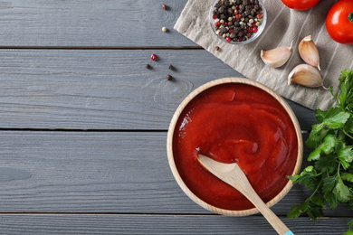 Flat lay composition with tomato sauce on grey wooden table, space for text