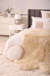 Stylish soft light bedroom interior with large comfortable bed, chest of drawers and bedside table