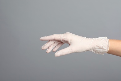 Photo of Doctor wearing medical gloves on grey background, closeup