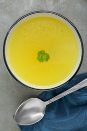 Delicious chicken bouillon with parsley on grey table, top view