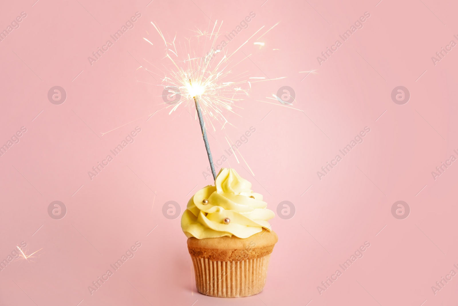 Photo of Birthday cupcake with sparkler on pink background