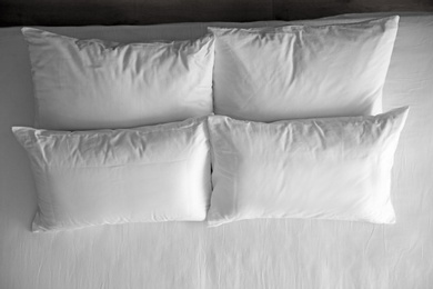 Soft pillows on comfortable bed, top view