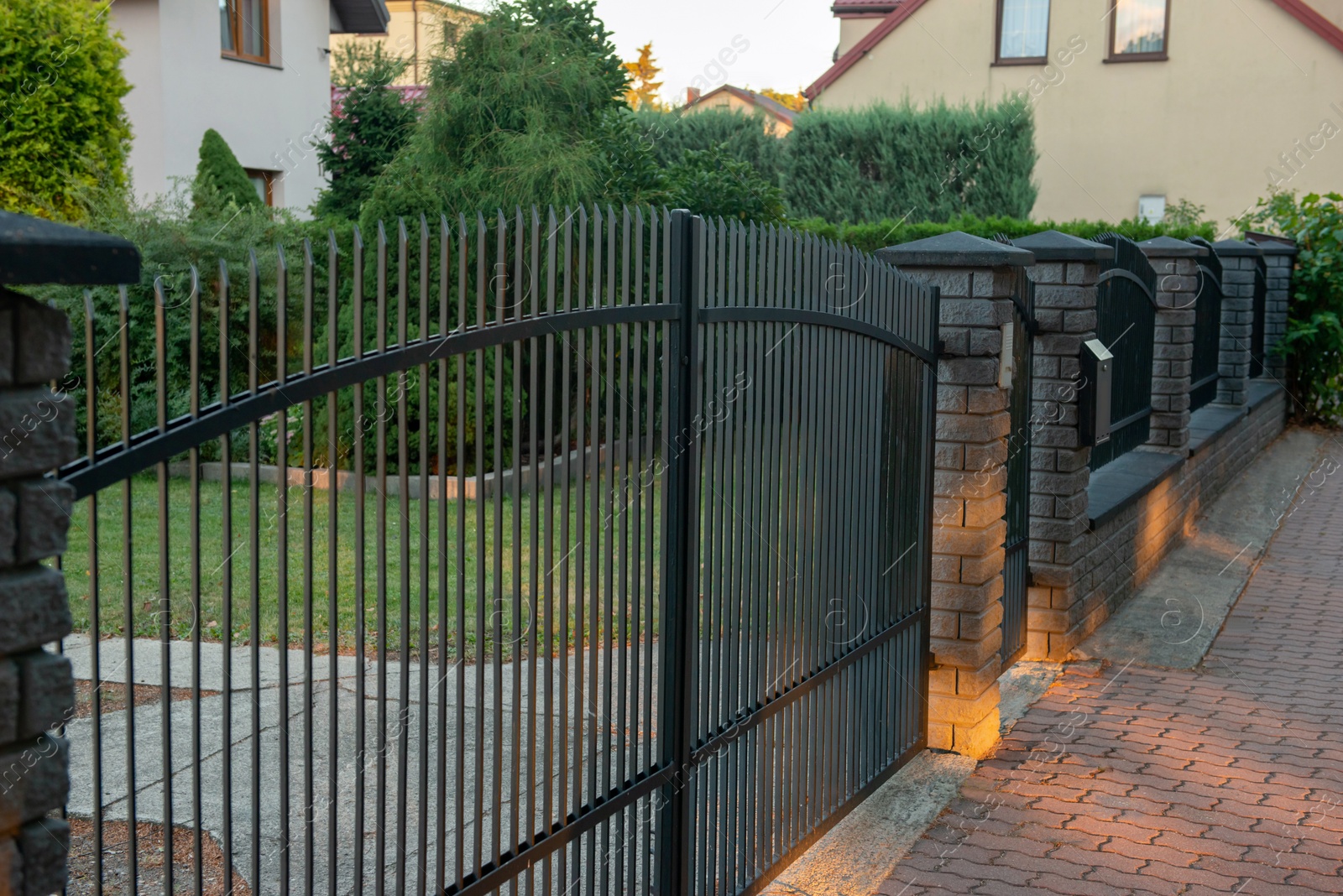 Photo of Beautiful brick fence with iron railing outdoors