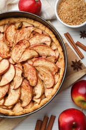 Photo of Delicious apple pie and ingredients on white wooden table, flat lay