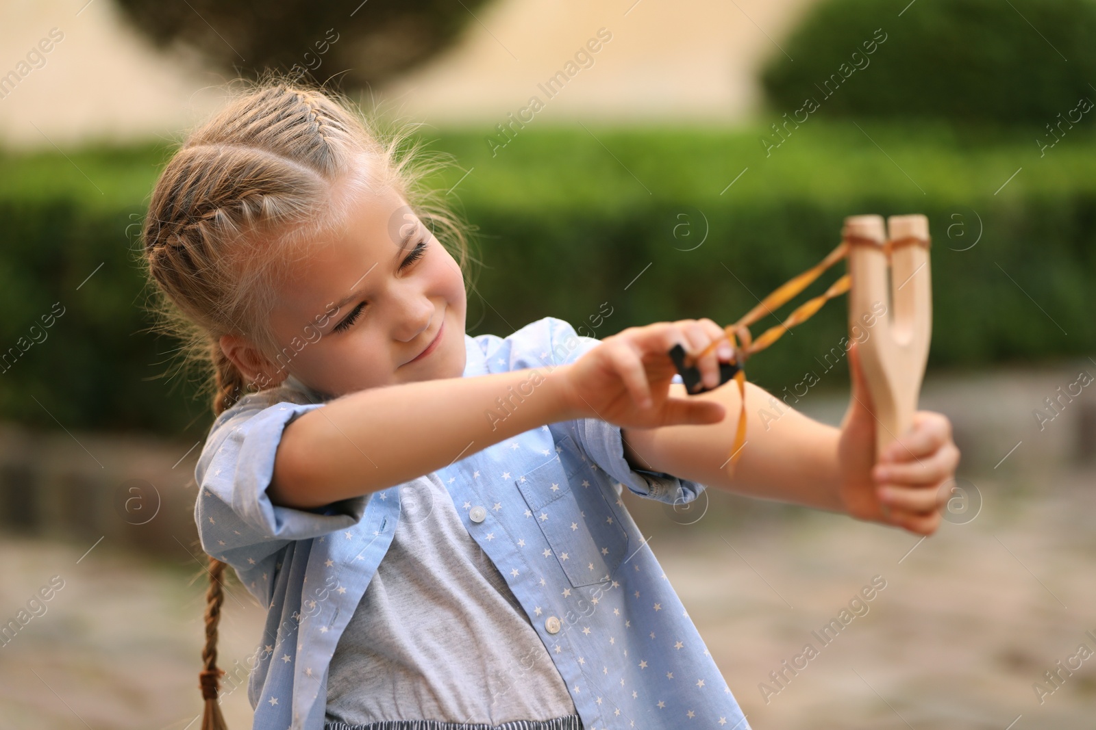 Photo of Little girl playing with slingshot in park