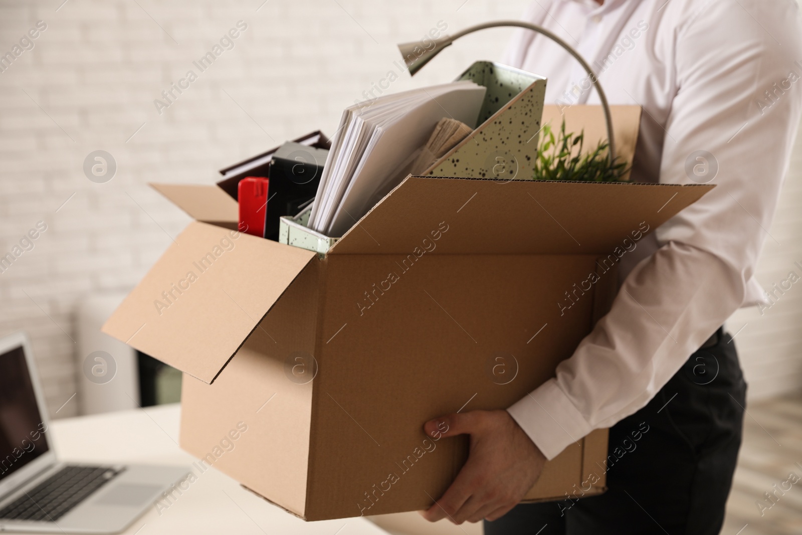 Photo of Young man with box of stuff in office, closeup