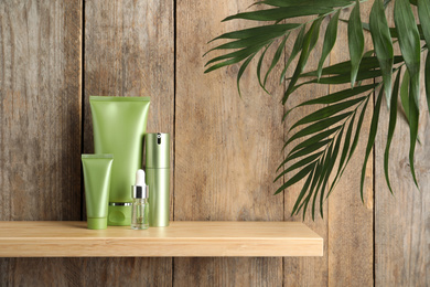 Photo of Set of cosmetic products on shelf near wooden wall