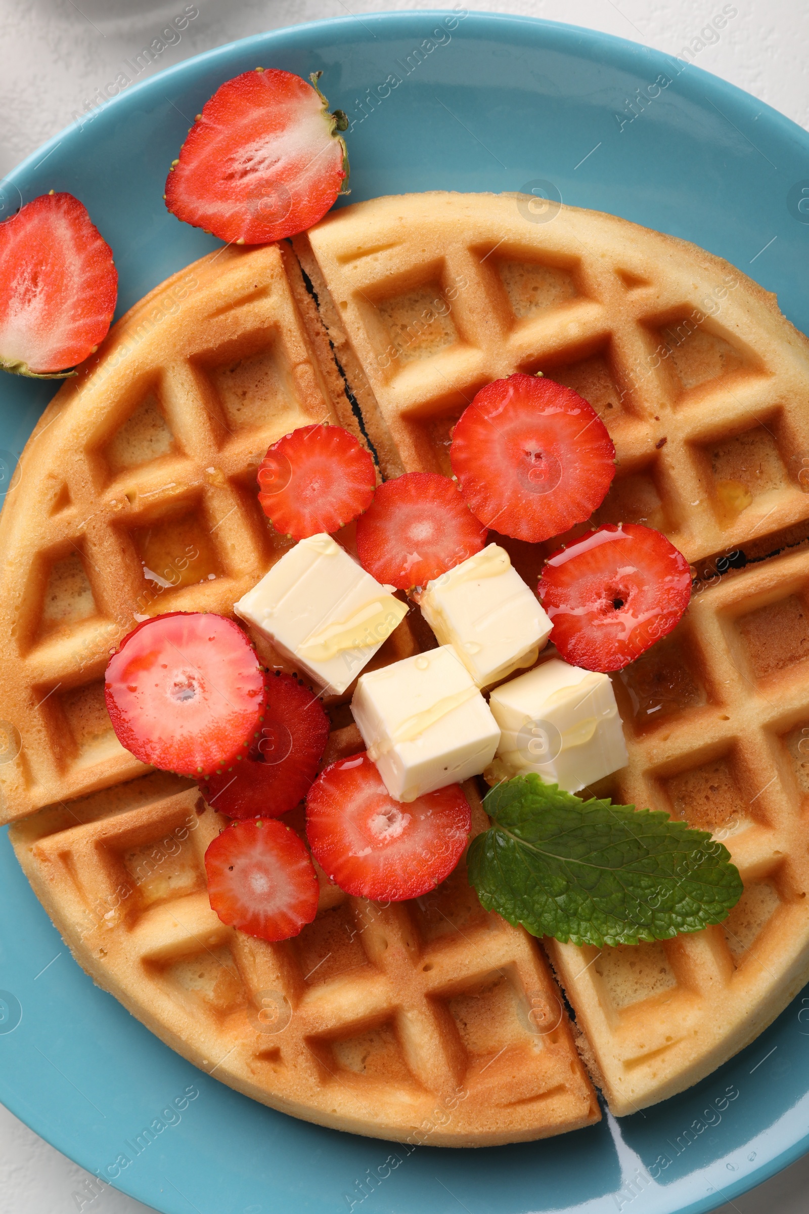 Photo of Tasty Belgian waffle with strawberries, cheese and honey on table, top view