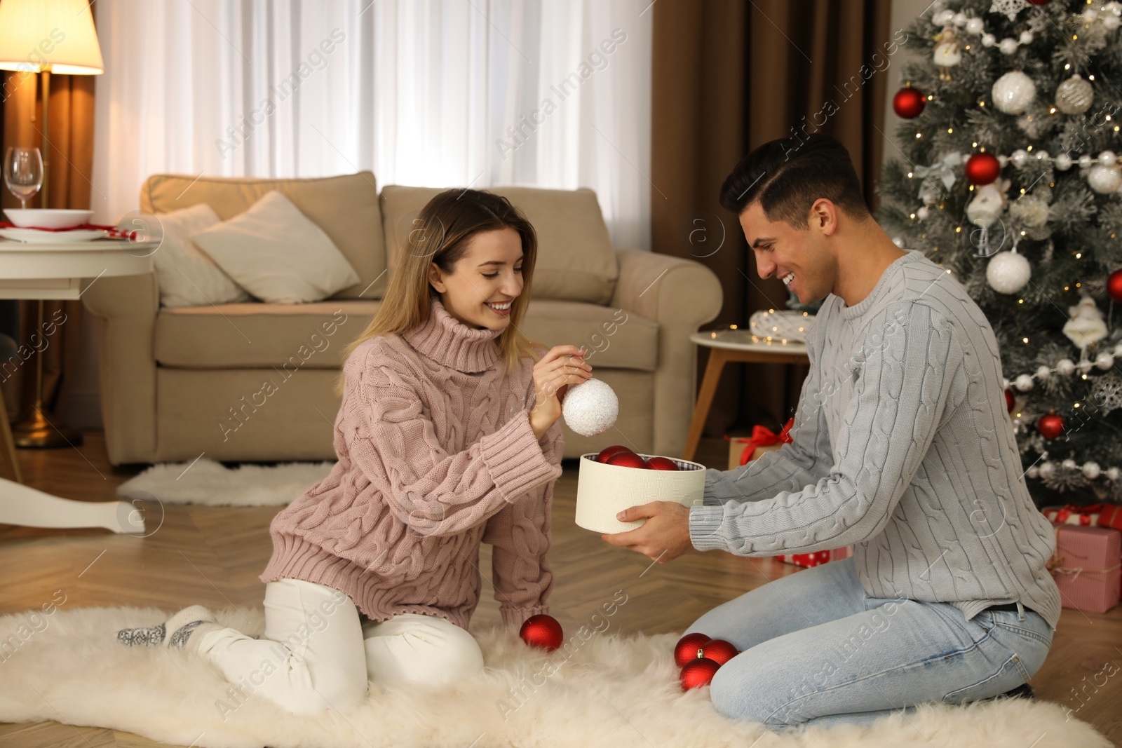 Photo of Couple decorating Christmas tree together at home