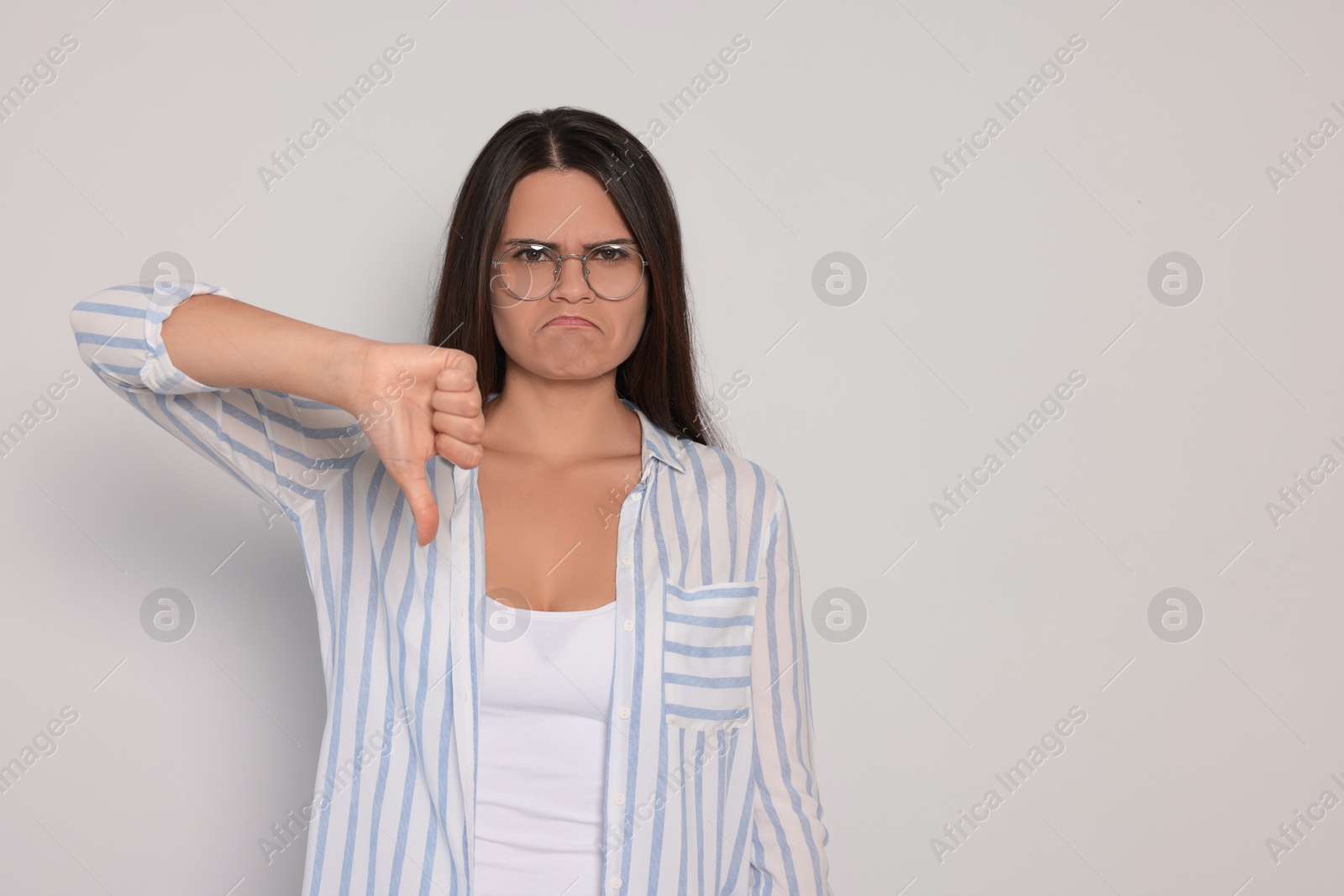 Photo of Young woman showing thumb down on white background, space for text