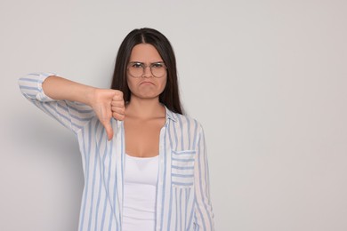 Photo of Young woman showing thumb down on white background, space for text