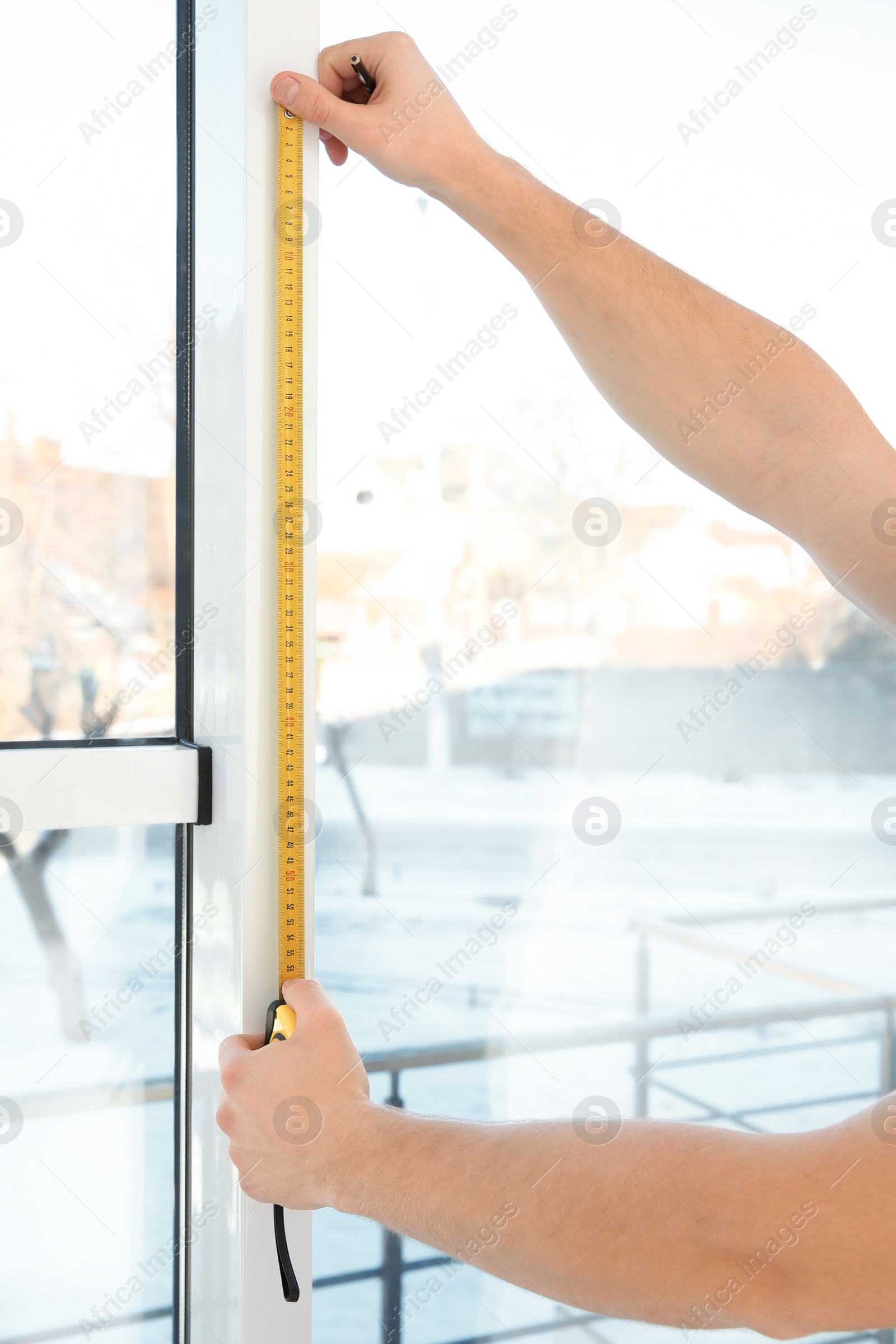 Photo of Service man measuring window for installation indoors, closeup