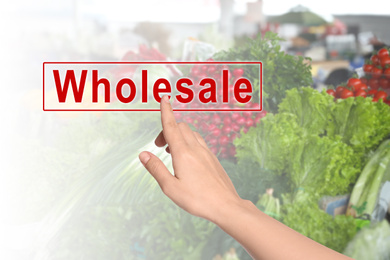 Woman clicking Wholesale button and blurred view of market counter with fresh goods on background 