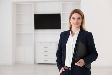 Photo of Happy real estate agent with leather portfolio indoors. Space for text