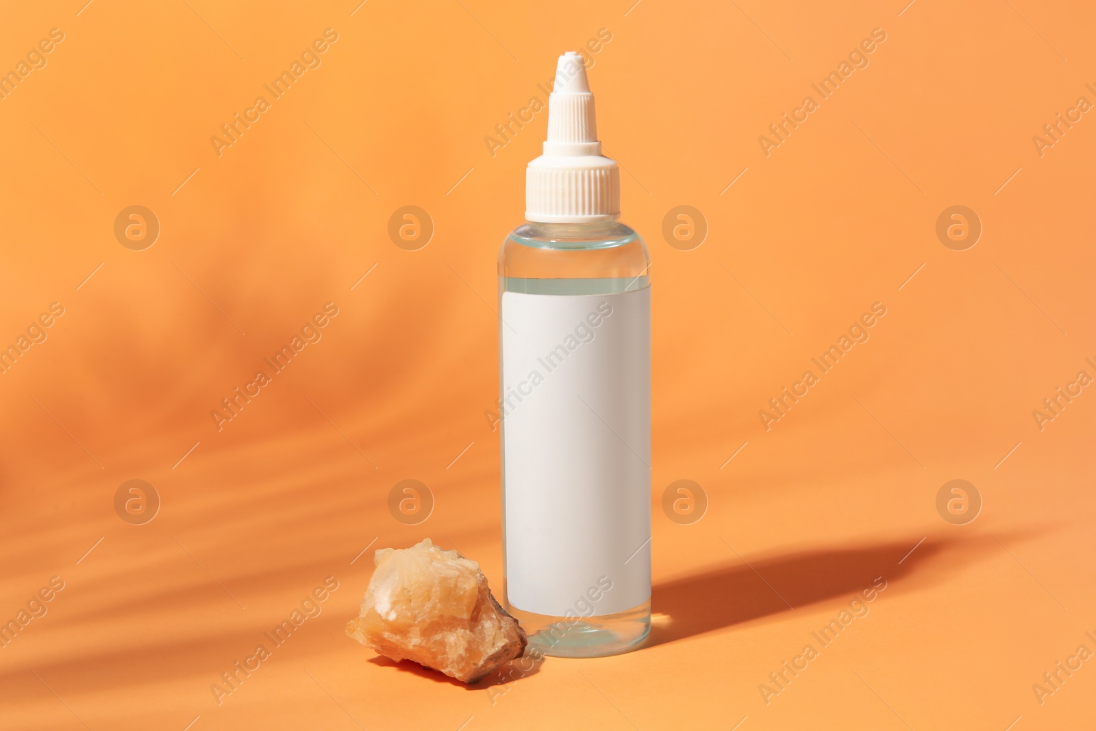 Photo of Cosmetic product and quartz gemstone on orange background