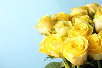 Beautiful bouquet of yellow roses on light blue background, closeup. Space for text