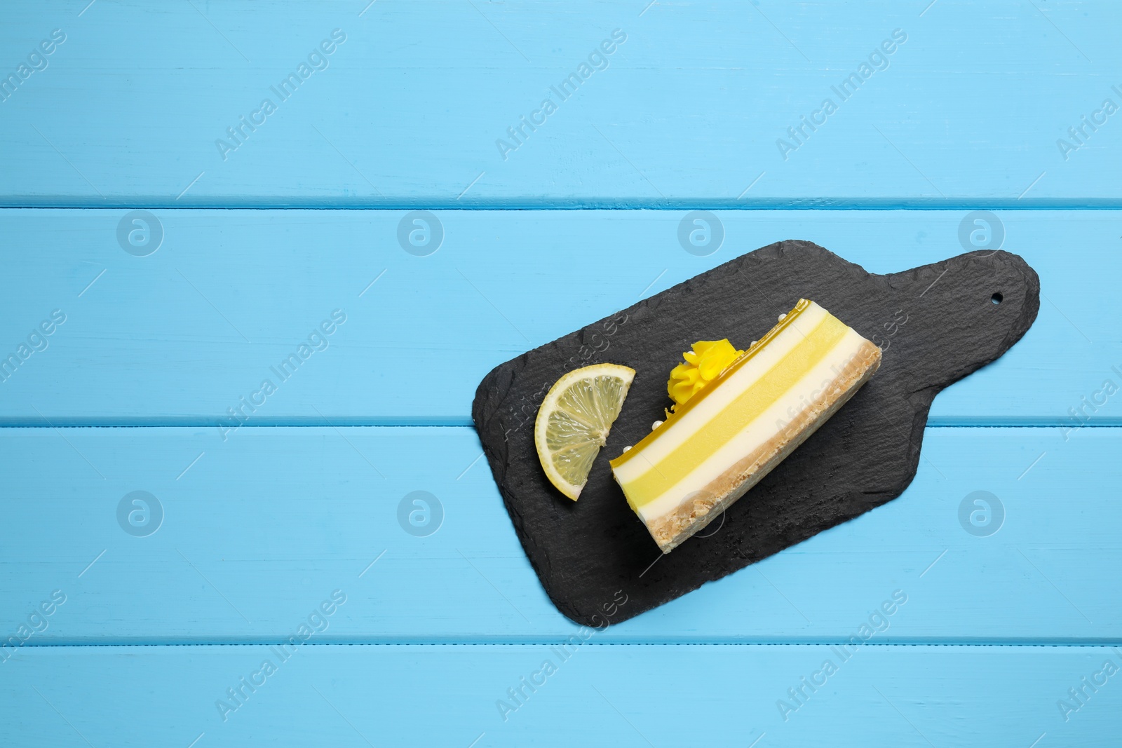 Photo of Delicious cheesecake with lemon on light blue wooden table, top view. Space for text