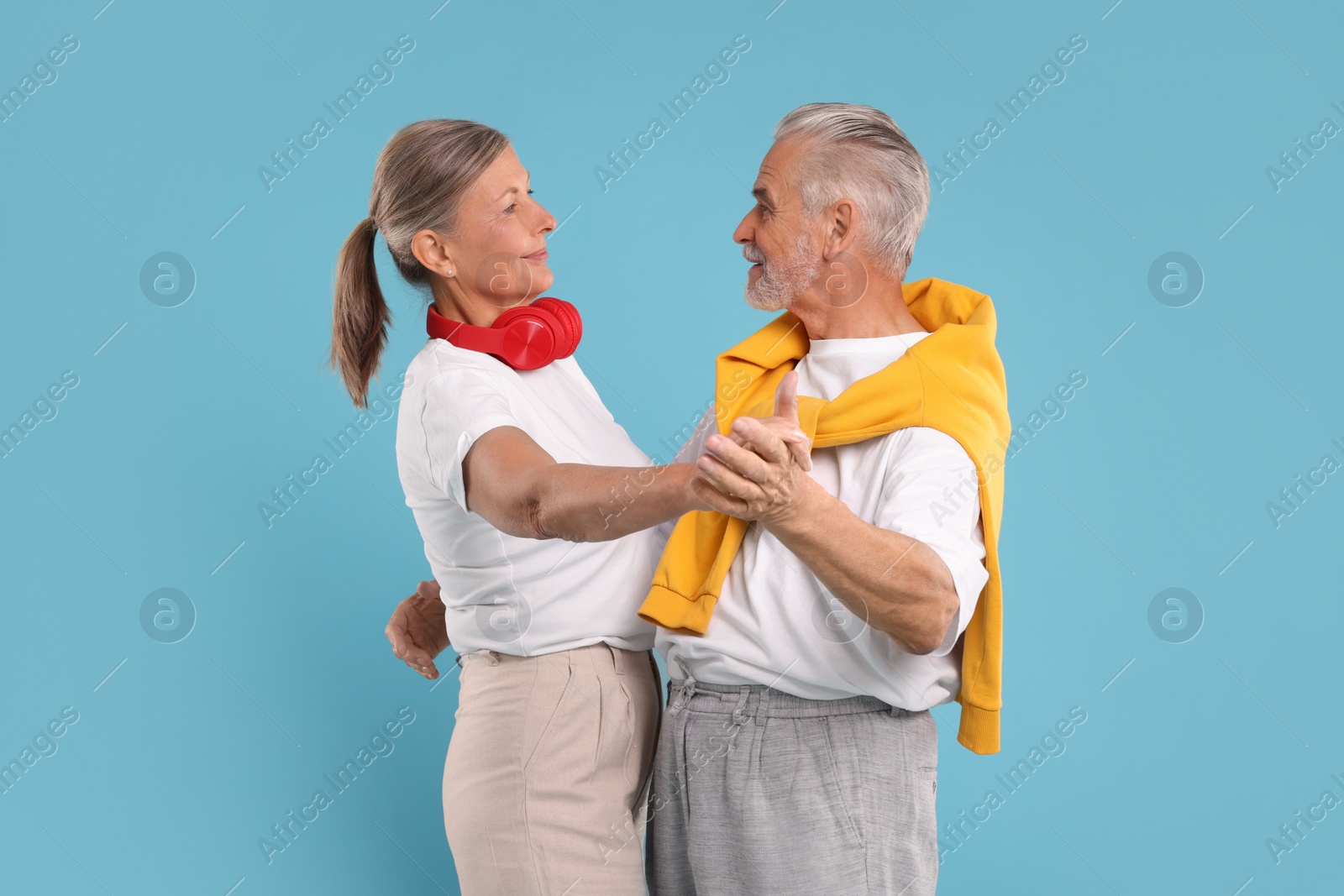 Photo of Senior couple dancing together on light blue background