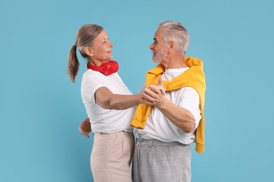 Senior couple dancing together on light blue background