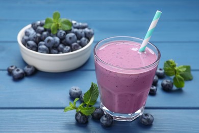 Photo of Glass of blueberry smoothie with mint and fresh berries on blue wooden table. Space for text