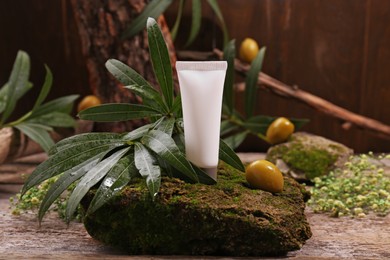 Tube of cream, olives and leaves on wooden table