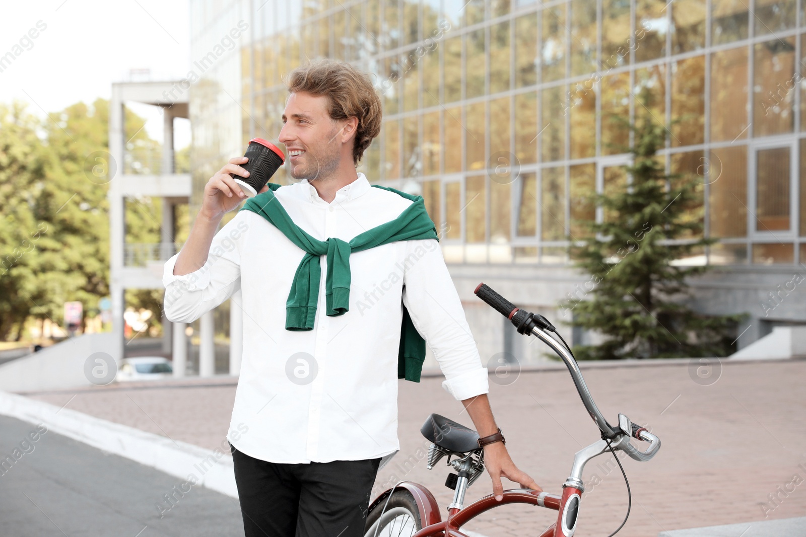 Photo of Attractive man with bike and cup of coffee on city street